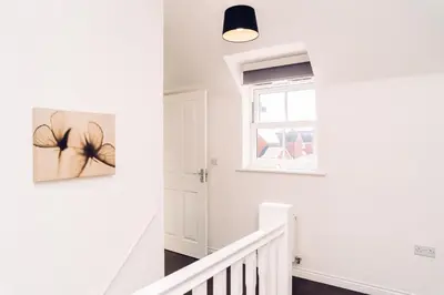 a white staircase in a home with a window at Detached Coach House in Colchester