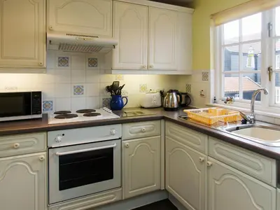 a kitchen with white cabinets and a sink at 1 Bell Lodge, Thorpeness in Thorpeness