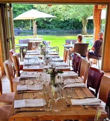 a long wooden table with wine glasses and napkins at Bedingfeld Arms in Swaffham