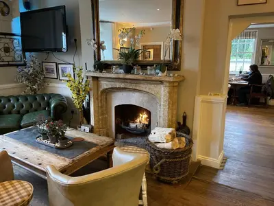 a living room with a fireplace and a green couch at Bedingfeld Arms in Swaffham