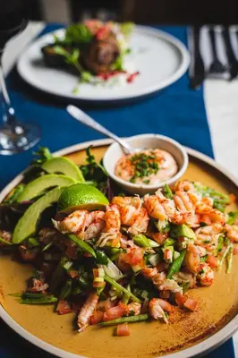 a plate of food with shrimp and vegetables on a table at The Bull Inn in Woolpit