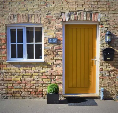 a yellow door and a window on a brick building at The Old Bottle Store - 2 Double Bedrooms, 2 Bathrooms, St Ives, Cambridgeshire in St Ives