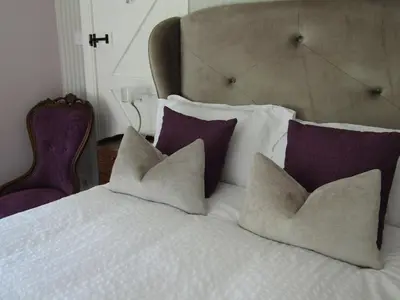 a white bed with purple pillows and a large headboard at Frogs Hall B&B in Eye