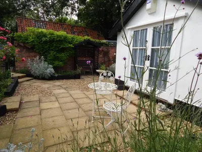 a garden with a chair and a table in front of a house at Frogs Hall B&B in Eye