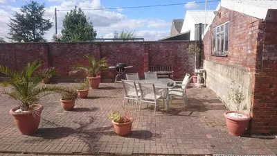 a patio with a table and chairs and potted plants at PERFECT BUSINESS ACCOMMODATION at SIDINGS FARM - Luxury Cottage Accommodation - Fully equipped & Self Catering in Pidley