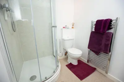 a bathroom with a shower and a toilet with purple towels at PERFECT BUSINESS ACCOMMODATION at SIDINGS FARM - Luxury Cottage Accommodation - Fully equipped & Self Catering in Pidley