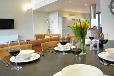 a table with glasses of wine and flowers on it at King George Penthouse in Aldeburgh