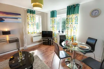 a living room with a table and chairs and a tv at Meridian Apartment Suites in Southend-on-Sea