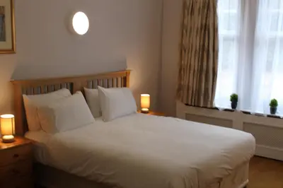 a bedroom with a white bed with two lamps on tables at Brookside Lodge in Baldock