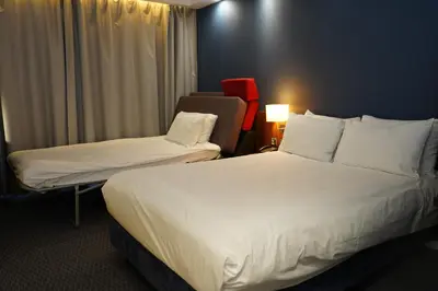 a hotel room with two beds and a chair at Holiday Inn Express Harlow by IHG in Harlow