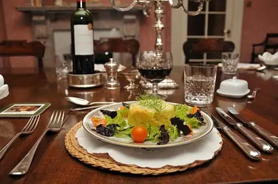 a plate of salad on a table with a bottle of wine at Haughley House in Stowmarket