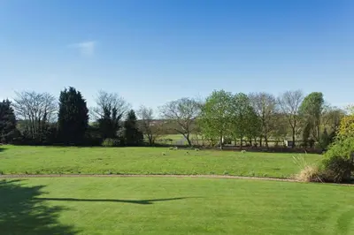 a field of grass with sheep in the distance at Haughley House in Stowmarket