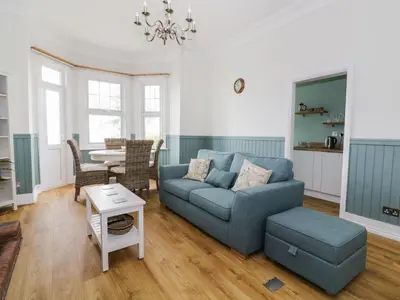 a living room with a blue couch and a table at Flat 1, Cambridge Court in Frinton-on-Sea