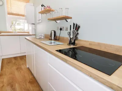 a kitchen with white cabinets and a black stove top oven at Flat 1, Cambridge Court in Frinton-on-Sea