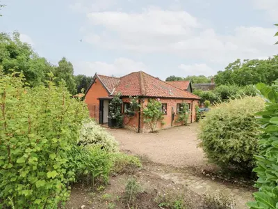an old brick house in the middle of a garden at Lowbrook Cottage in Diss