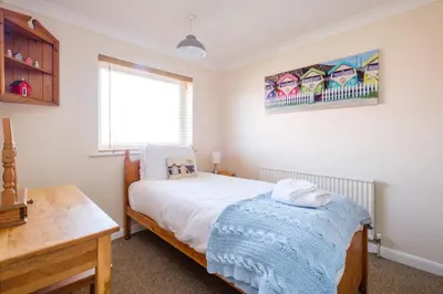 a bedroom with a bed with a blue blanket on it at Poplars in Aldeburgh