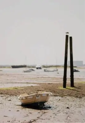 a boat sitting on a beach next to two poles at The Blackwater Suite in West Mersea