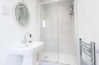 a white bathroom with a sink and a shower at The Blackwater Suite in West Mersea