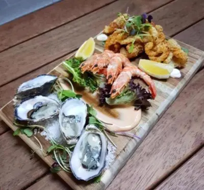 a plate of seafood and oysters on a wooden table at The Blackwater Suite in West Mersea