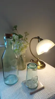 a table with a lamp and a glass vase with flowers at 1 WATER PUMP HOUSE in Bury Saint Edmunds