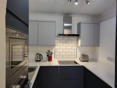 a kitchen with white appliances and black cabinets at 1 WATER PUMP HOUSE in Bury Saint Edmunds