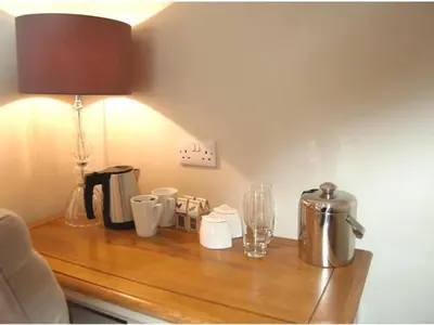 a wooden table with a lamp and cups on it at The Red Cow in Heydon