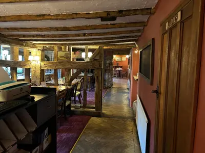 a hallway with a dining room with a table and a television at The Red Cow in Heydon