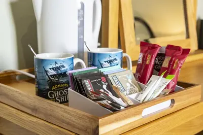 a wooden tray with two mugs and books on a table at The Cross Keys, Aldeburgh in Aldeburgh