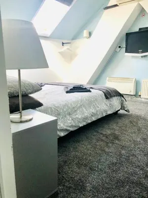 a bedroom with a bed and a table with a lamp at AC Hideout in Rochford