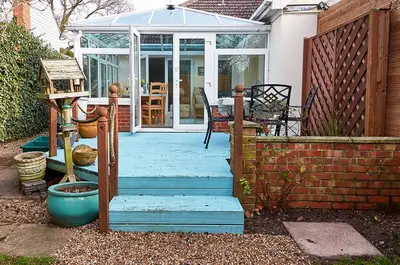 a house with a conservatory with a glass door and stairs at Sunshine Corner in West Mersea