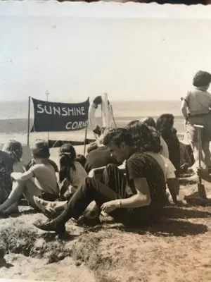 a group of people sitting on the beach at Sunshine Corner in West Mersea