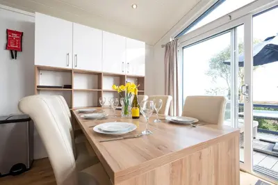 a dining room table with white chairs and a large window at Horizon Lodge in Sizewell