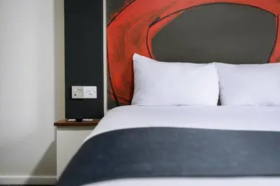 a bed with white pillows and a red head board at Ramada London Stansted Airport in Stansted Mountfitchet