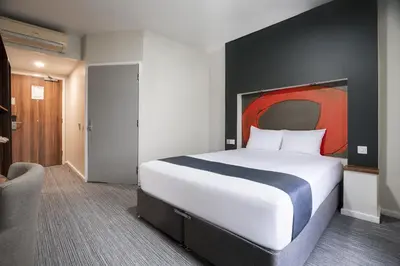 a bedroom with a large bed with a red painting on the wall at Ramada London Stansted Airport in Stansted Mountfitchet