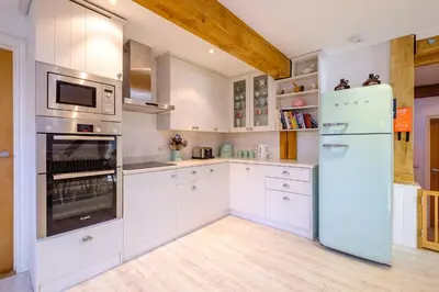 a kitchen with white cabinets and a refrigerator at Meare House in Thorpeness