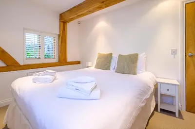 a bedroom with a white bed with towels on it at Meare House in Thorpeness