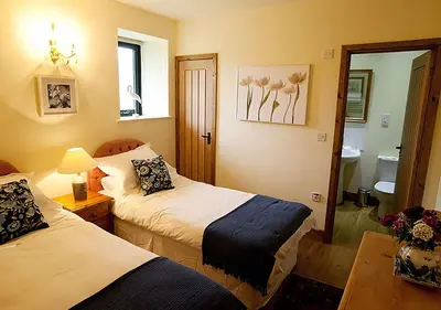 a hotel room with two beds and a bathroom at Lackford Lakes Barns in Flempton