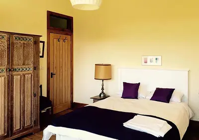a bedroom with a bed with purple pillows and a lamp at Lackford Lakes Barns in Flempton