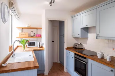 a kitchen with white cabinets and a sink at Puddleduck Cottage in Aldeburgh