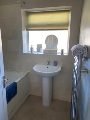 a bathroom with a sink and a mirror and a tub at By Buildersbeds - Hill House 3 Bedrooms in Romford