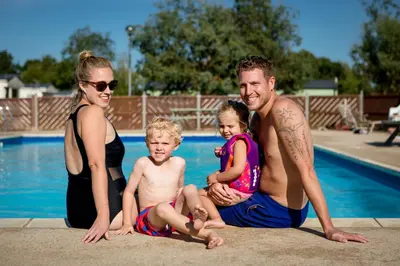 a family is posing by a swimming pool at Camping Pods, Carlton Meres Holiday Park in Rendham