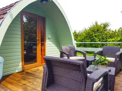 a green house with wicker chairs on a deck at Colemans Cottage Fishery in Wickham Bishops