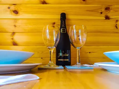 a bottle of wine and two wine glasses on a table at Colemans Cottage Fishery in Wickham Bishops