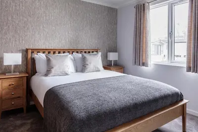 a bedroom with a large bed and a window at Roydon Marina Village Lodges in Roydon