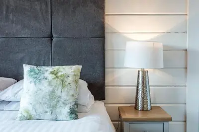 a bed with a pillow and a lamp on a table at Roydon Marina Village Lodges in Roydon