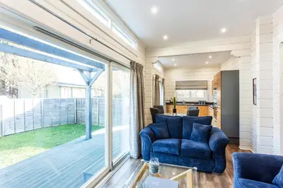 a living room with a blue chair and a sliding glass door at Roydon Marina Village Lodges in Roydon