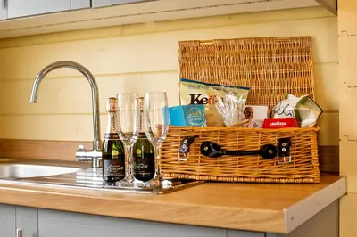 a basket of wine bottles and glasses on a kitchen counter at Sunset log cabin in Sudbury