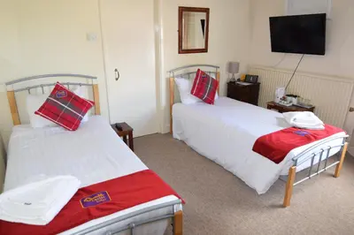 a hotel room with two beds and a flat screen tv at Castle Lodge in Ely