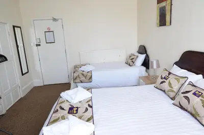 a hotel room with two beds and a chair at Castle Lodge in Ely