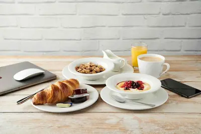 a table with two plates of breakfast food and a laptop at The Aviator, formerly Smugglers Cove, Clacton On Sea by Marston's Inns in Clacton-on-Sea